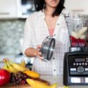 Woman making fruit smoothie in kitchen